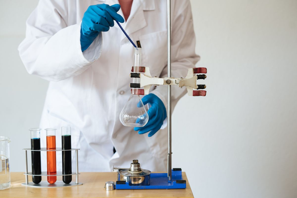 Laboratory technician in gloves working with labeled test tubes and glassware during sample analysis